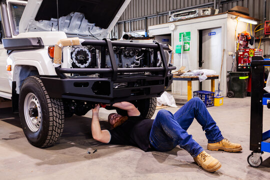 mechanic working under new car build being fitted out as part of a mining fleet