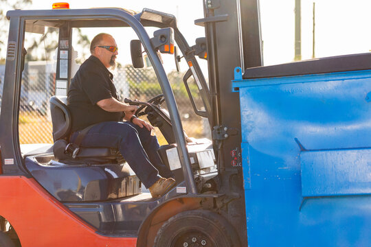 Forklift operator using machinery to move industrial bins around site