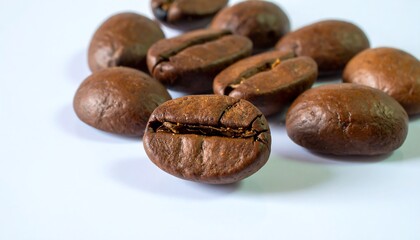 Obraz premium Close-up view of roasted coffee beans, displaying rich brown tones and textured surfaces against a clean white background.