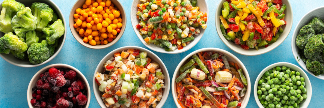 A top view of colorful, frozen vegetables on plates, highlighting the process of preserving summer best produce for nutritious winter meals, banner,, vegetables in plates on a blue background