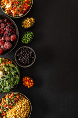 Fresh fruits and vegetables, frozen and placed in plates, on a dark backdrop, symbolizing the process of summer preparations for the colder months ahead