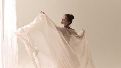 The language of softness. Graceful woman in flowing veil dance with soft light. Concept of...