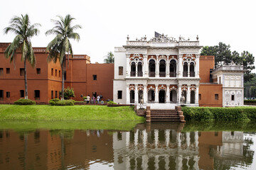 Sonargaon, Bangladesh - 12 October 2024: View of the serene Goaldi Mosque reflected in tranquil waters, framed by lush greenery and clear skies, creating a picturesque scene of cultural heritage.