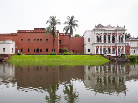 Sonargaon, Bangladesh - 12 October 2024: View of the vibrant red brick facade of Panam Nagar juxtaposed against the serene reflection in the surrounding water body.