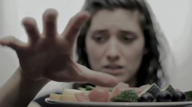 Intense food aversion display, woman rejects a platter of fresh fruits and vegetables with