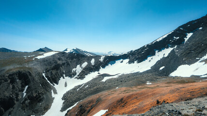 Majestic mountain range with snowy peaks against blue sky displays beautiful contrast, highlighting natural diversity and grandeur.