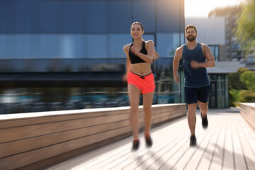 Man and woman in sportswear running outdoors, motion blue effect
