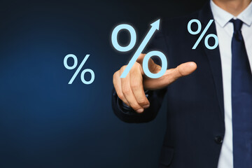 Businessman touching virtual percent sign against dark blue background, closeup