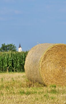 Strohballe mit Kirchturm im Hintergrund, vertikal