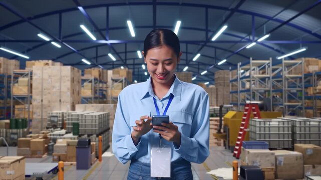 Asian Female With Her Smarphone in Warehouse with Rows of Shelving, Work Continuously On Her Device - Powered by Adobe