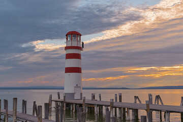 Two wooden piers on Neusiedler See with Podersdorf Lighthouse, glowing sunset sky reflecting softly on the lake surface