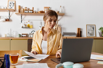 Bright sunny afternoon finds a young woman focused on her work in the inviting kitchen.