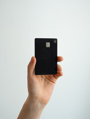 Hand showing black bank card on white surface. Perfect for mobile apps, social media, communication, digital lifestyle and technology design, payment online, bank, bussines 