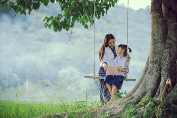 A village girl and her younger sister are happily reading together. The older sister is having fun...