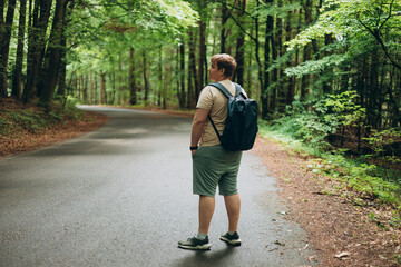 Young 30s man hiking in nature. Travel, adventure. Concept of an active lifestyle. High quality photo. Back view. Hiker man standing outdoor at nature forest, full body © mdyn