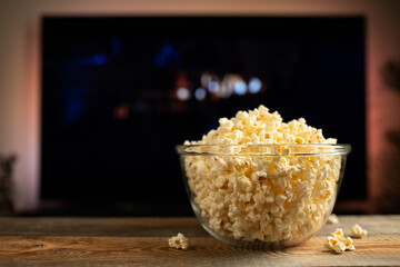 A glass bowl of popcorn and remote control in the background the TV works