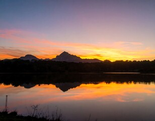 Obraz premium Sunset over tranquil lake with mountains