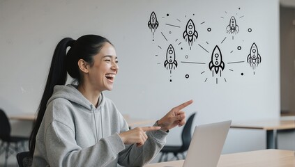 Woman working on laptop with rocket icons and laughing