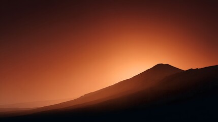 Obraz premium A silhouette volcanic ridge with glowing orange twilight sky above