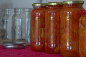 Red tomato and onion mix in clear glass jars on kitchen counter top ready for storage