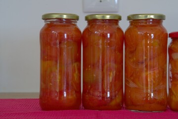 Red tomato and onion mix in clear glass jars on kitchen counter top ready for storage