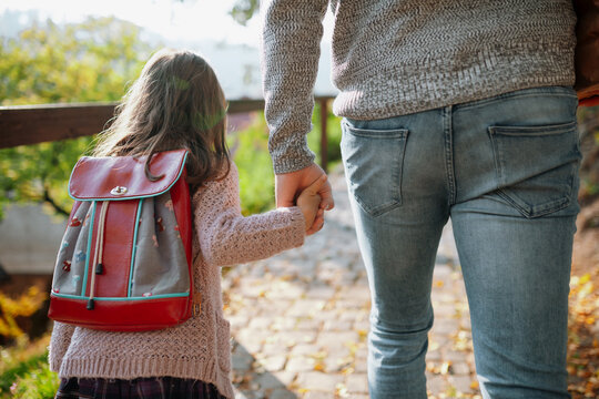 Parent walking child to school on first day, holding hands. - Powered by Adobe