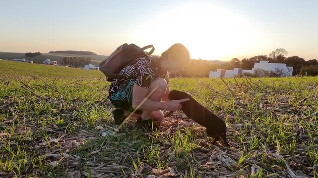 homem com cachorro fofo duchshund em p&ocirc;r do sol 