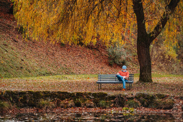 Pensive older man sitting on bench by lake and thinking.