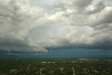 Dark stormy clouds forming on gloomy sky before heavy rainfall over suburban town area