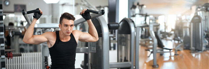 Man Exercising in Gym on Machine Wide Banner with Copy Space