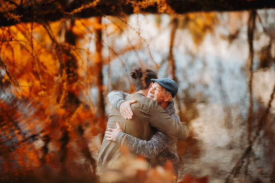Grandad and grandson hugging in the middle of autumn park. - Powered by Adobe