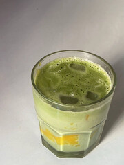 Green matcha latte layered with mango chunks.