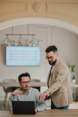 Fototapeta premium Two businessmen collaborating on laptop in modern office