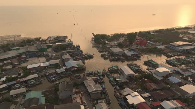 An aerial shot of a vibrant fishing village in Sekinchan, where colorful boats are docked in tight formation along narrow canals, flanked by red-roofed wooden houses and modern buildings beyond.