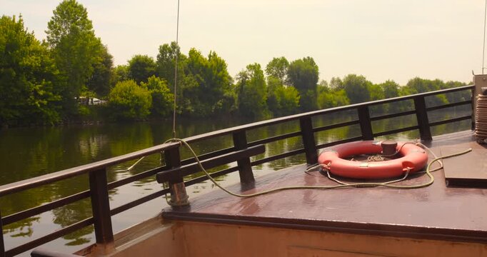 Sailing through Dordogne river on a traditional boat in France with lush, dense banks . 4k.