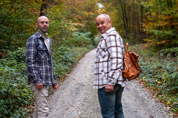 Fototapeta premium Two men walking together, Happy Mature friends walking together, Older father and young adult son, autumn walk, casual talk, active aging, adult relationship, warm bond, family connection