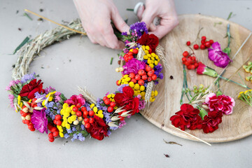 Florist at work: woman shows how to make an autumn door wreath with rowan berry and tansy. Step by step, tutorial.