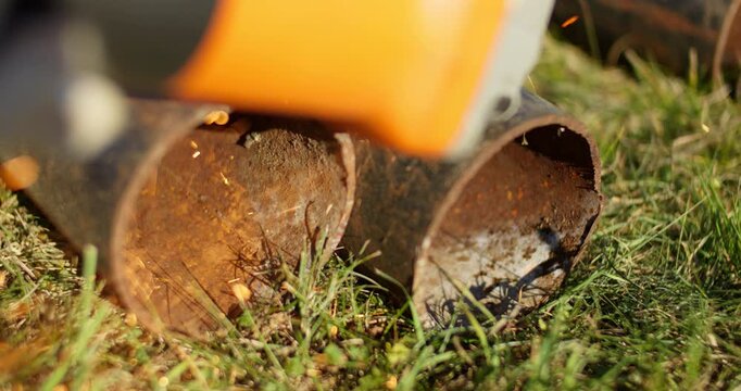 Sparks from an angle grinder fly onto the grass on a sunny summer day in slow motion