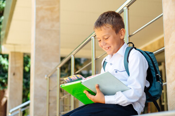 back to school, a boy sitting with his textbooks at school and doing his homework, a student going to school in September