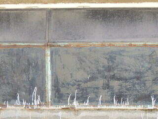 an old, peeling, dilapidated wall made of a dull-textured hard material, stitched with metal ties with a corrosion effect, a fragment of the outer wall of a utility building with paint smudges