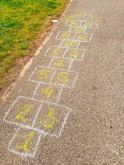 A hopscotch game drawn with chalk on the pavement in the park. Childhood, nostalgia and playful leisure activity connecting imagination with movement and joy.