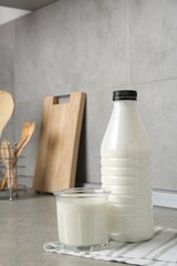 Dairy products. Fresh milk in glass and bottle on gray textured table indoors