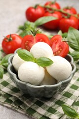 Tasty mozzarella cheese balls, tomatoes and basil on table, closeup