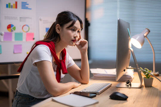 A woman is sitting at a desk with a computer monitor in front of her