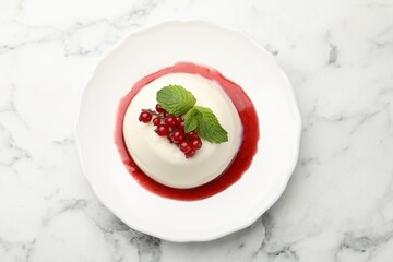 Delicious panna cotta with red currants, sauce and mint on white marble table, top view