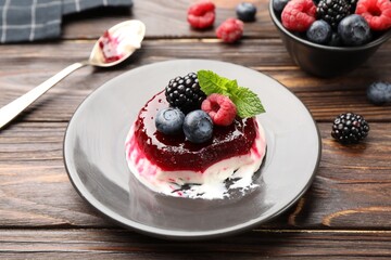 Delicious panna cotta with berries, jam and mint on wooden table, closeup