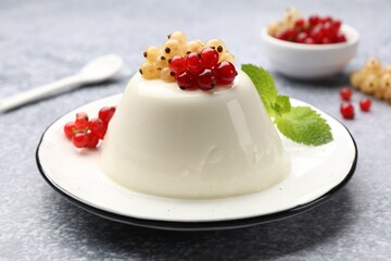 Tasty panna cotta with currants and mint on light grey table, closeup