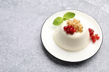 Tasty panna cotta with currants and mint on light grey table, closeup. Space for text