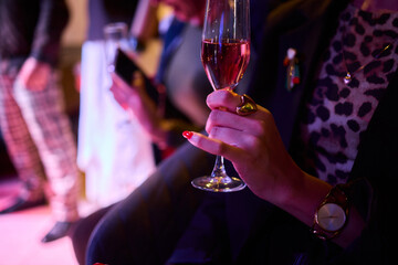 Elegant Hand Holding a Glass of Ros Champagne at an Event