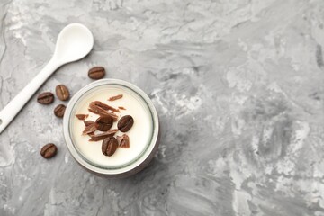Delicious panna cotta with chocolate chunks and coffee beans on grey textured table, flat lay. Space for text